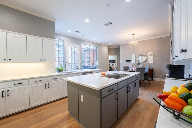 kitchen with black electric stovetop, a center island, sink, white cabinetry, and light hardwood / wood-style flooring