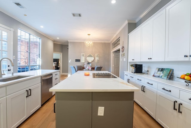 kitchen with stainless steel dishwasher, white cabinets, sink, and a kitchen island