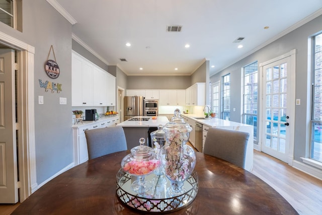 dining space featuring dark wood-type flooring, ornamental molding, and sink