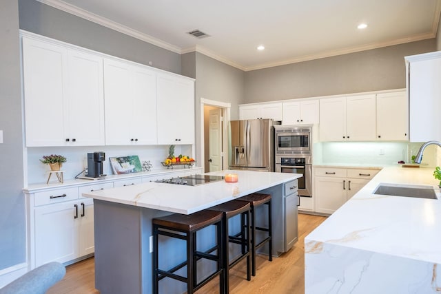 kitchen with appliances with stainless steel finishes, a kitchen breakfast bar, a kitchen island, white cabinets, and sink