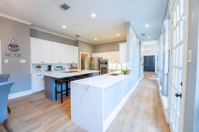 kitchen with light hardwood / wood-style floors, white cabinetry, a center island, and a breakfast bar area