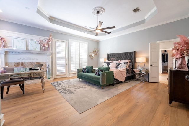 bedroom featuring a raised ceiling, ceiling fan, light wood-type flooring, and ornamental molding