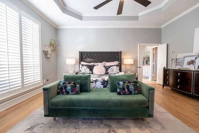 bedroom with ceiling fan, ornamental molding, light hardwood / wood-style floors, and a raised ceiling