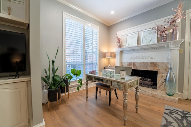 office with light wood-type flooring, crown molding, and a tile fireplace