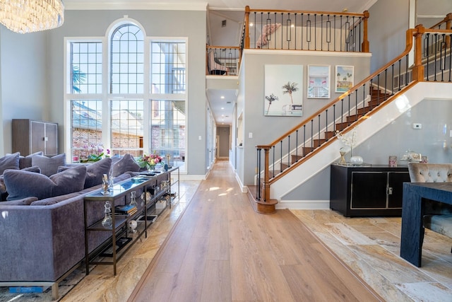 living room with crown molding, a towering ceiling, and a healthy amount of sunlight