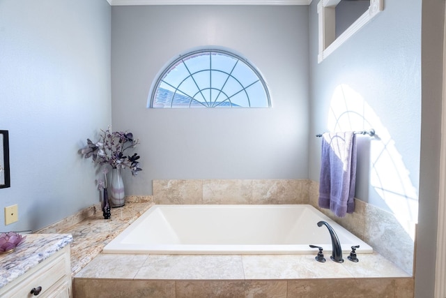 bathroom with tiled tub and vanity