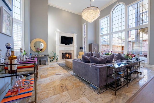 living room with crown molding, a towering ceiling, a premium fireplace, and an inviting chandelier