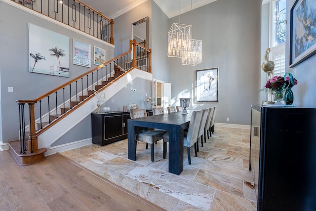 dining area featuring a high ceiling, light wood-type flooring, ornamental molding, and an inviting chandelier