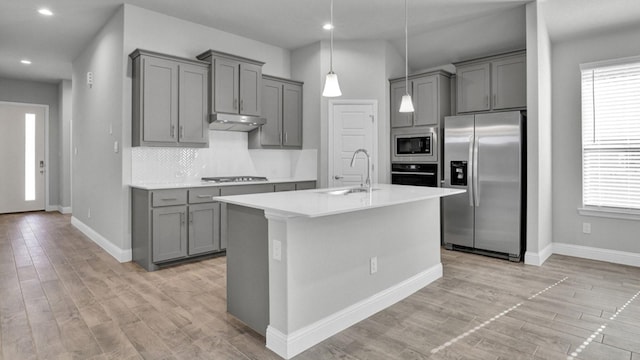 kitchen with tasteful backsplash, decorative light fixtures, gray cabinets, sink, and stainless steel appliances