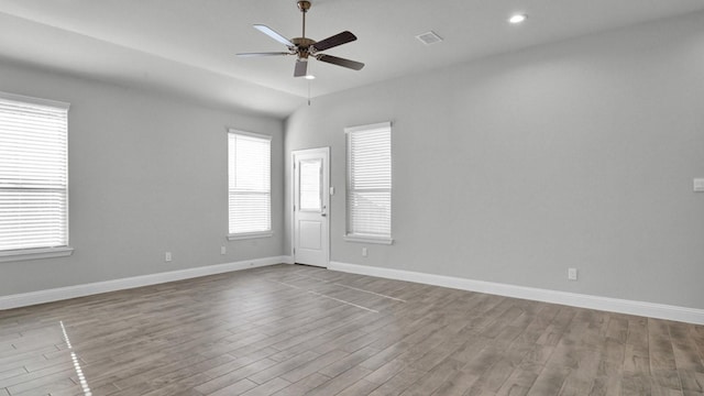 unfurnished room with light wood-type flooring, ceiling fan, vaulted ceiling, and plenty of natural light