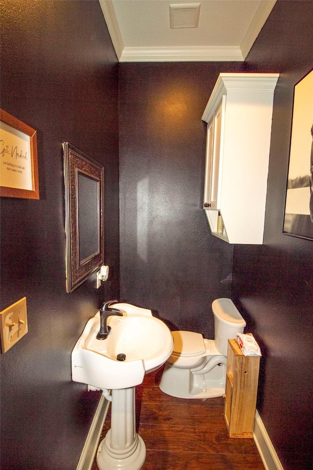 bathroom with toilet, crown molding, wood-type flooring, and sink