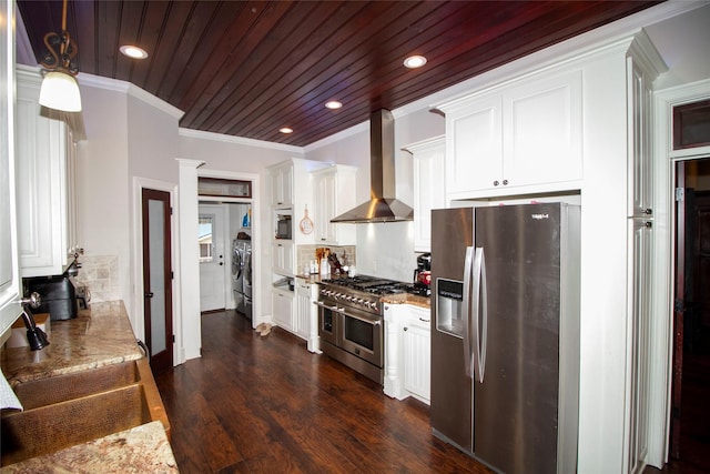 kitchen with wall chimney range hood, white cabinets, stainless steel appliances, and washing machine and clothes dryer