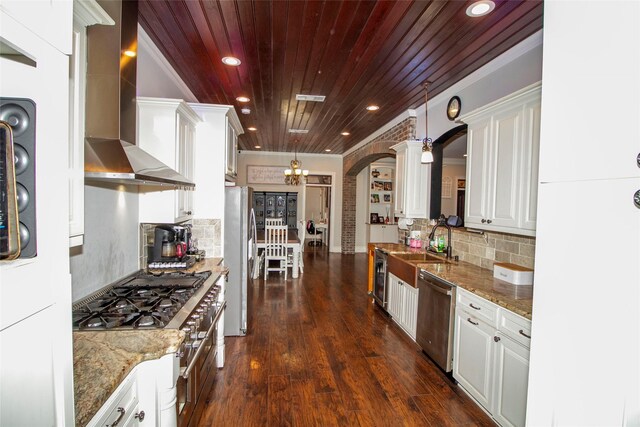 4201 Linda Ln, Shreveport, LA 71107 - kitchen featuring wall chimney exhaust hood, stainless steel appliances, decorative columns, wood ceiling, and white cabinets