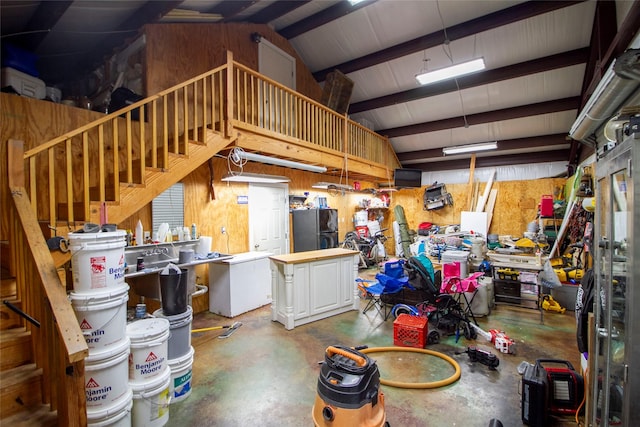 garage featuring black refrigerator, fridge, wood walls, and a workshop area