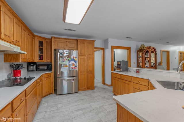 kitchen featuring sink, backsplash, stainless steel refrigerator, and black electric cooktop