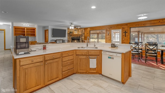 kitchen with a textured ceiling, dishwasher, a fireplace, sink, and ceiling fan