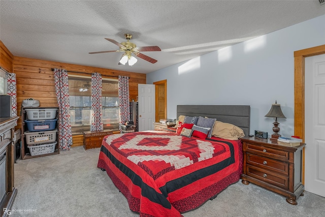 bedroom featuring ceiling fan, light colored carpet, wood walls, and a textured ceiling