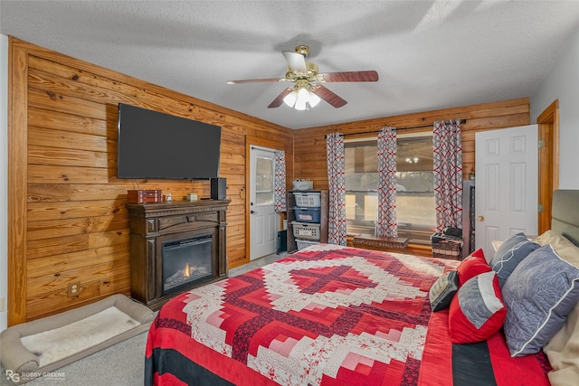 carpeted bedroom with a textured ceiling, ceiling fan, and wooden walls