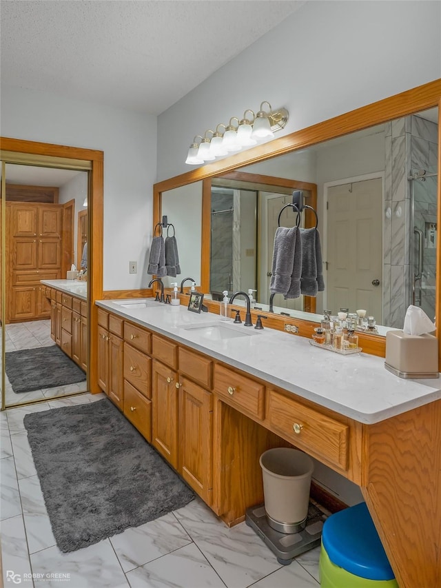 bathroom featuring an enclosed shower, vanity, and a textured ceiling