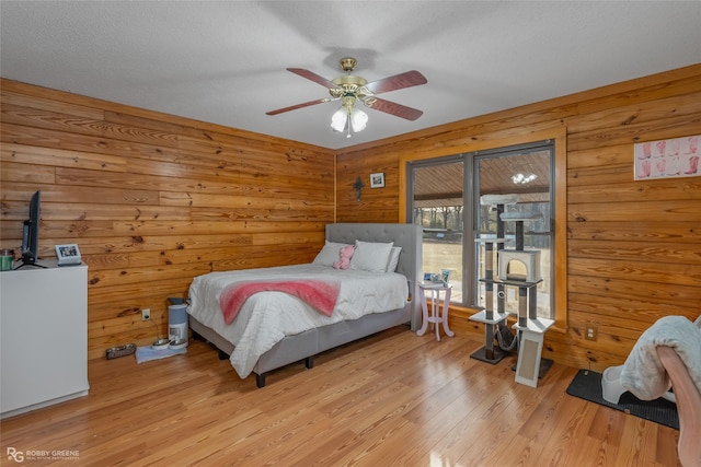 bedroom with a textured ceiling, ceiling fan, and light hardwood / wood-style floors