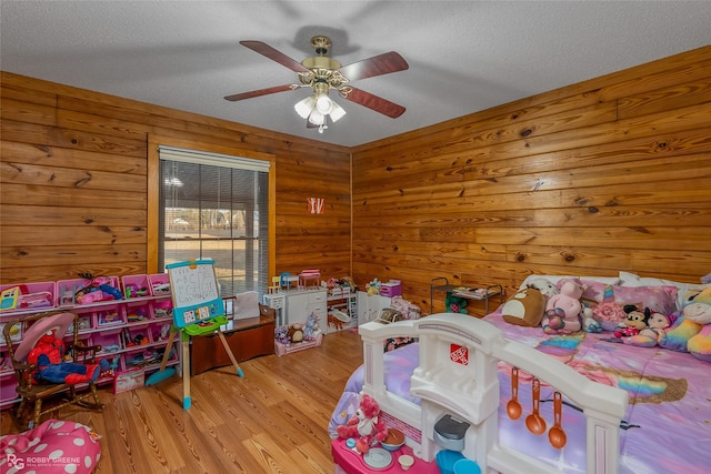 bedroom with a textured ceiling, ceiling fan, and light hardwood / wood-style flooring