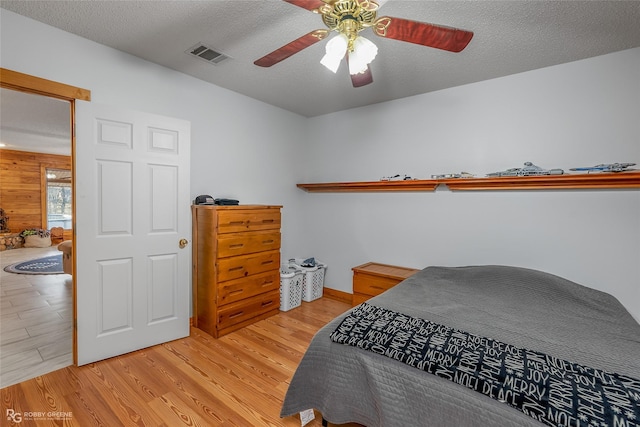 bedroom featuring ceiling fan, light wood-type flooring, and a textured ceiling