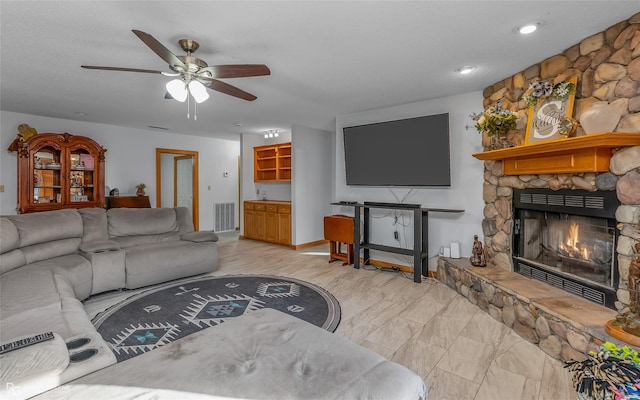 living room featuring ceiling fan and a stone fireplace