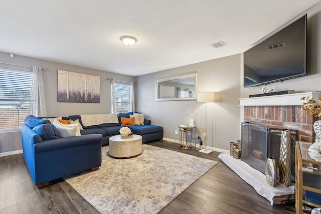 living room with a brick fireplace and dark wood-type flooring