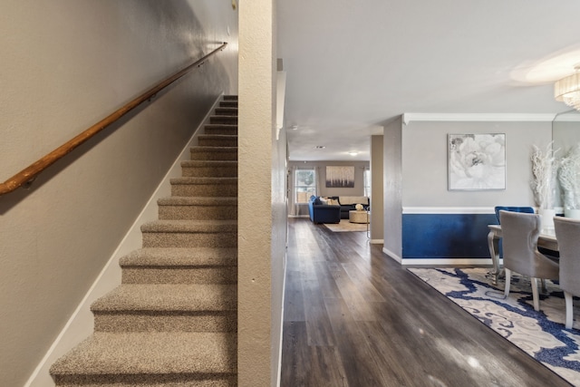 staircase featuring a chandelier, crown molding, and hardwood / wood-style floors