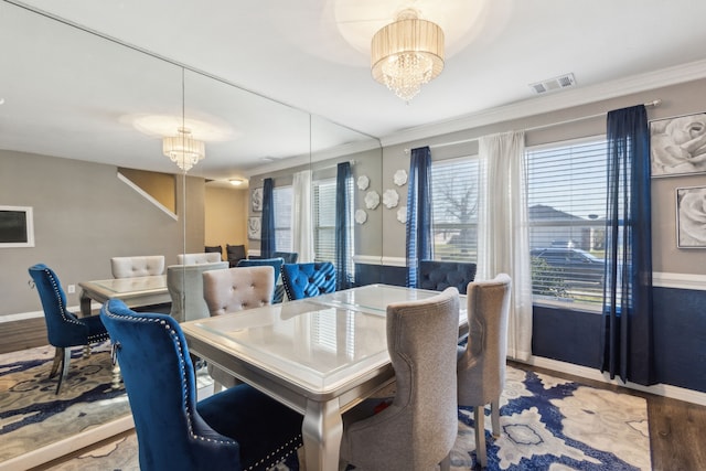 dining space featuring crown molding, an inviting chandelier, and light hardwood / wood-style flooring