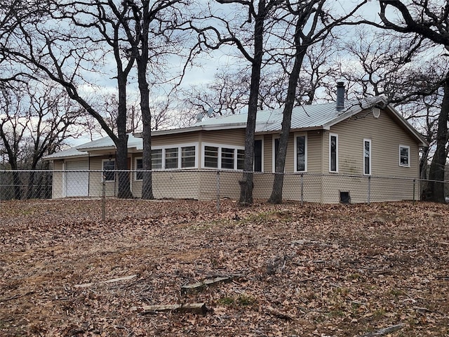 view of front facade featuring a garage, metal roof, and fence