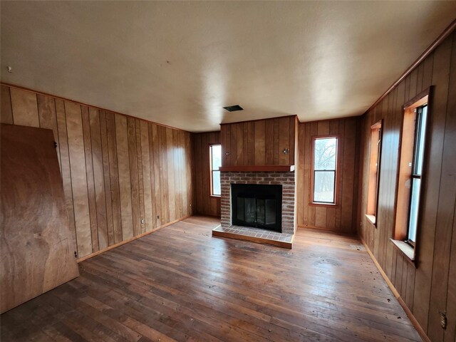 unfurnished living room featuring wood walls, hardwood / wood-style floors, and a fireplace