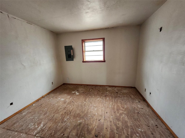 spare room with wood finished floors, electric panel, and baseboards