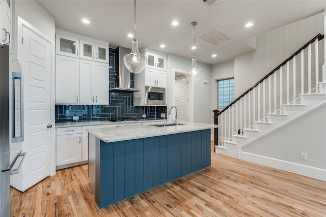 kitchen with a center island with sink, sink, white cabinetry, hanging light fixtures, and stainless steel appliances