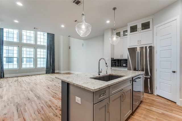 kitchen with decorative light fixtures, white cabinetry, sink, gray cabinets, and a kitchen island with sink