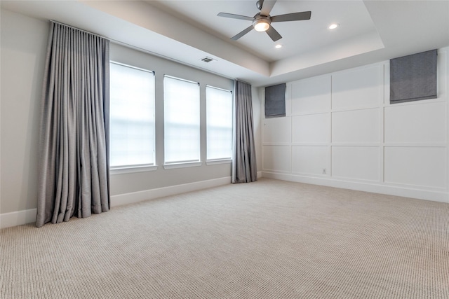 carpeted spare room featuring ceiling fan and a tray ceiling