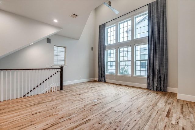 unfurnished room with ceiling fan, a high ceiling, a wealth of natural light, and light hardwood / wood-style flooring