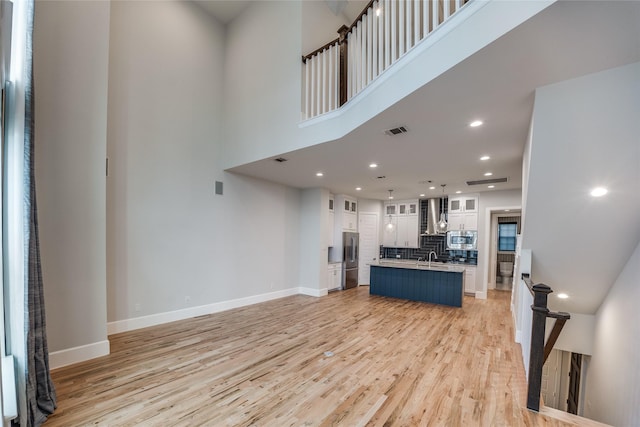 living room with light hardwood / wood-style floors, a towering ceiling, and sink