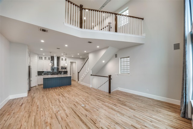 unfurnished living room featuring light wood-type flooring and a high ceiling