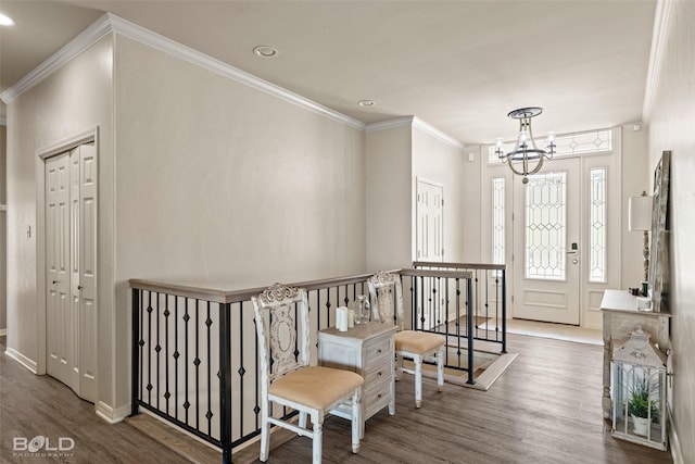 entryway with dark wood-type flooring, crown molding, and an inviting chandelier