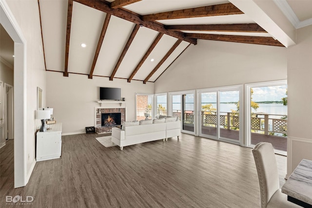 unfurnished living room featuring a brick fireplace, beamed ceiling, dark hardwood / wood-style floors, and high vaulted ceiling