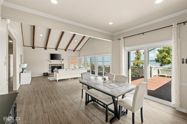 dining space featuring hardwood / wood-style floors, a tile fireplace, and lofted ceiling with beams