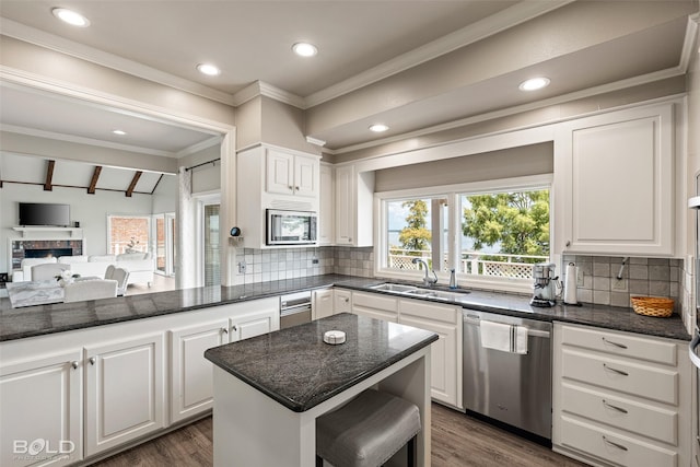 kitchen with dark stone countertops, lofted ceiling with beams, sink, appliances with stainless steel finishes, and white cabinets