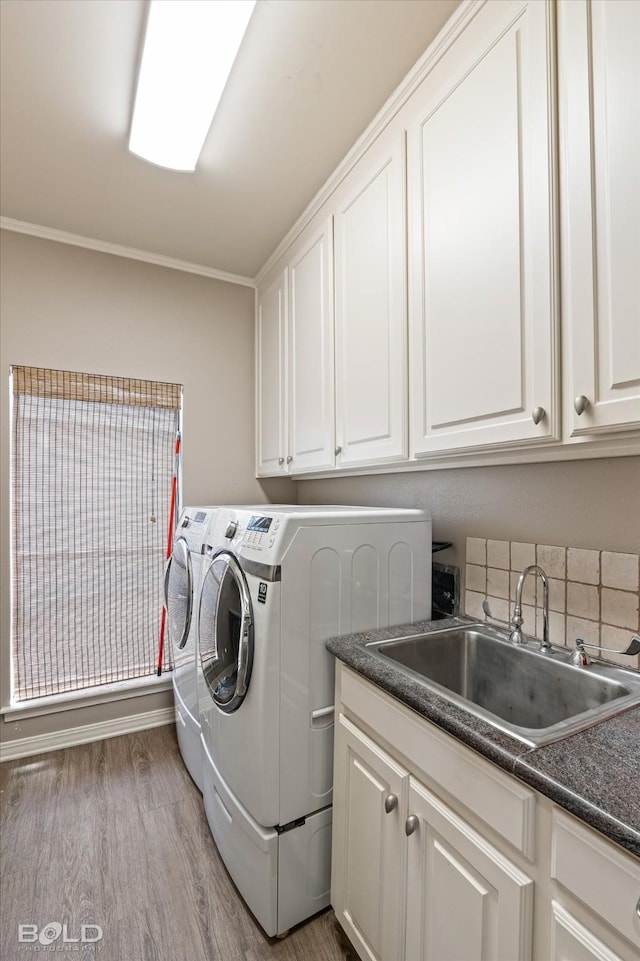 laundry room featuring cabinets, sink, ornamental molding, independent washer and dryer, and light wood-type flooring