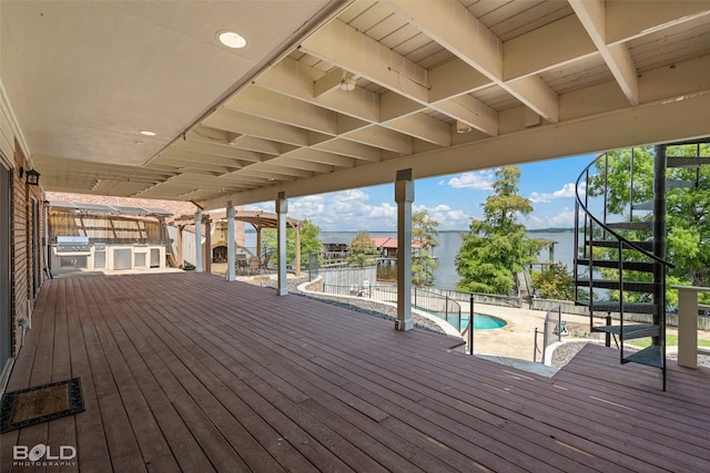 wooden deck featuring a water view, a grill, a fenced in pool, and area for grilling