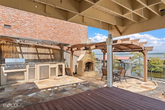 wooden terrace with a patio area, area for grilling, grilling area, a water view, and exterior fireplace