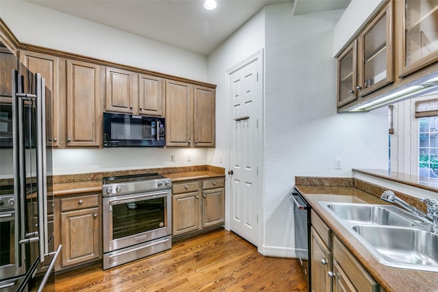 kitchen with appliances with stainless steel finishes, hardwood / wood-style flooring, and sink