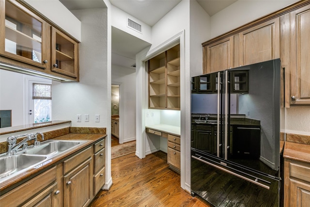 kitchen with black refrigerator, sink, and hardwood / wood-style flooring