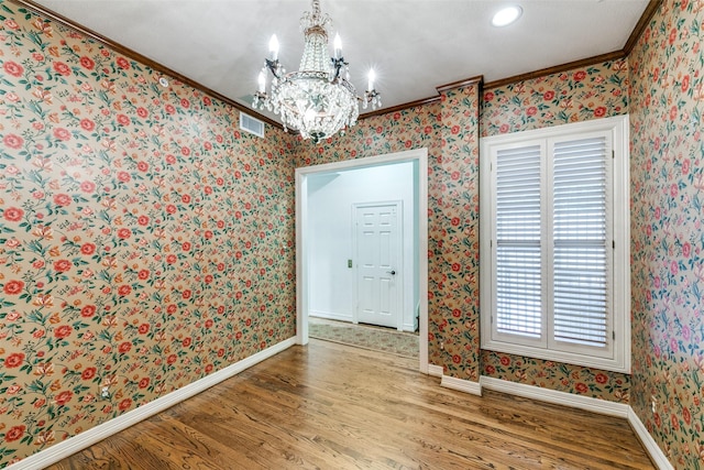 entryway featuring wood-type flooring, ornamental molding, and a notable chandelier