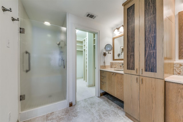 bathroom featuring a shower with shower door and vanity